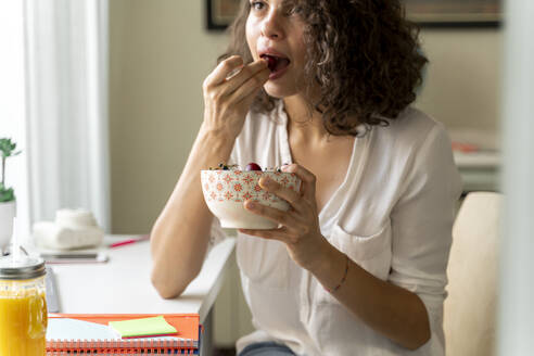 Junge Frau isst Obst am Schreibtisch - AFVF03725