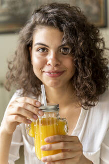 Porträt einer lächelnden jungen Frau mit einem Glas Orangensaft - AFVF03726