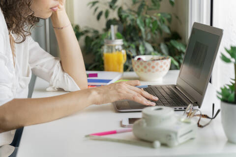 Nahaufnahme einer Frau, die einen Laptop am Schreibtisch benutzt, lizenzfreies Stockfoto