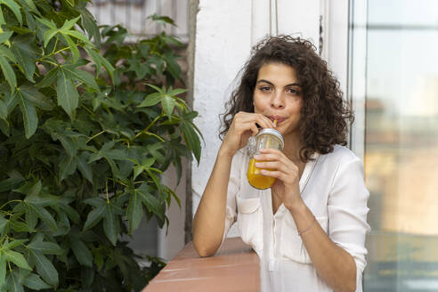 Porträt einer jungen Frau, die ein Glas Orangensaft trinkt - AFVF03747