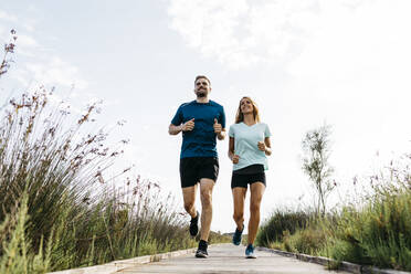 Young couple jogging on wooden walkway - JRFF03637