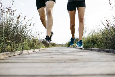 Junges Paar joggt auf einem Holzsteg - JRFF03640