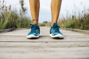 Füße einer Joggerin auf einer Holzpromenade - JRFF03647