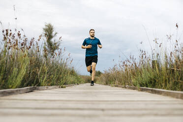 Jogger running on a wooden walkway - JRFF03653