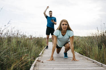 Joggerin mit ihrem Trainer auf einem Holzsteg - JRFF03664