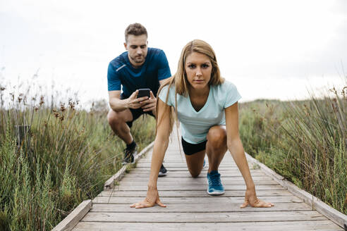 Joggerin mit ihrem Trainer auf einem Holzsteg - JRFF03665