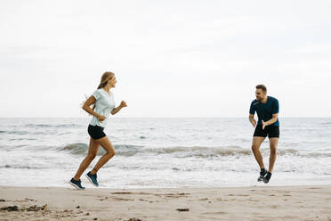 Joggerin am Strand mit ihrem Trainer - JRFF03672