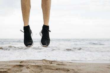 Beine eines Mannes, der beim Training an den Strand springt - JRFF03684