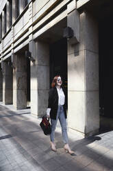 Geschäftsfrau, die auf der Straße geht und eine Tasche trägt - EYAF00368