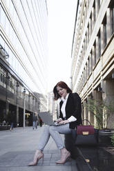 Businesswoman in the city, using laptop - EYAF00369