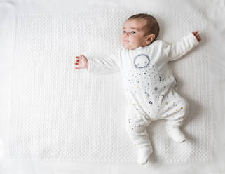 Ein kleiner Junge liegt im Bett auf einer weißen Decke - FLMF00204