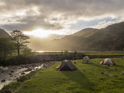 Zelte auf einer Wiese vor bewölktem Himmel bei Sonnenuntergang, Schottland, UK - HUSF00058