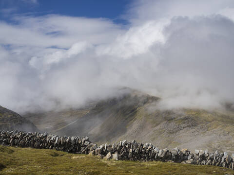 Steinmauer auf Berg gegen bewölkten Himmel, Schottland, UK, lizenzfreies Stockfoto