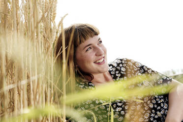 Porträt einer lächelnden jungen Frau in einem Kleid mit Blumenmuster in der Natur - FLLF00267