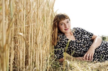 Porträt einer lächelnden jungen Frau in einem Kleid mit Blumenmuster in der Natur - FLLF00268