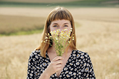 Porträt einer jungen Frau mit Kamillenblütenstrauß, lizenzfreies Stockfoto