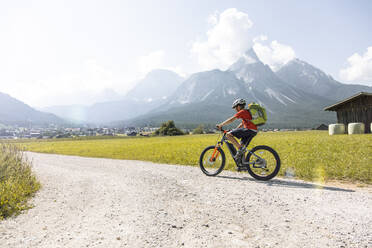 Junge fährt E-Mountainbike in den Bergen - FKF03530