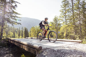 Frau fährt E-Mountainbike in den Bergen - FKF03534