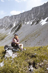 Mädchen macht eine Pause während einer Wanderung in den Bergen - FKF03542