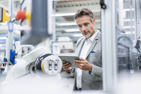 Businessman with tablet at assembly robot in a factory - DIGF07805