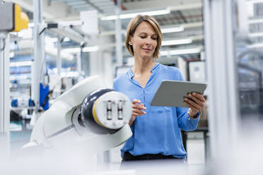 Businesswoman with tablet at assembly robot in a factory - DIGF07808