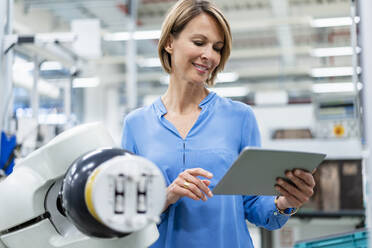 Businesswoman with tablet at assembly robot in a factory - DIGF07809