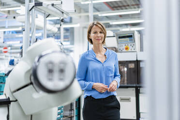 Porträt einer Geschäftsfrau an einem Montageroboter in einer Fabrik - DIGF07811