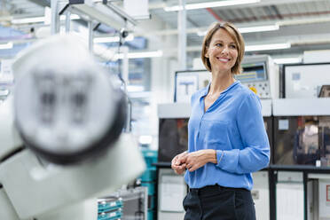 Portrait of businesswoman at assembly robot in a factory - DIGF07813