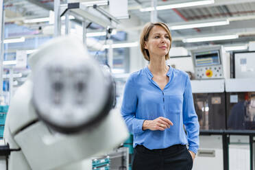 Portrait of businesswoman at assembly robot in a factory - DIGF07814