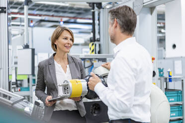 Businesswoman and man talking at assembly robot in a factory - DIGF07823