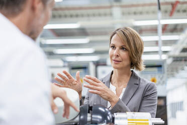 Businesswoman and man talking at assembly robot in a factory - DIGF07829