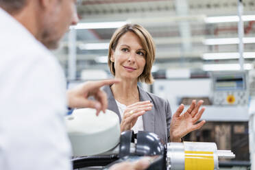 Businesswoman and man talking at assembly robot in a factory - DIGF07830