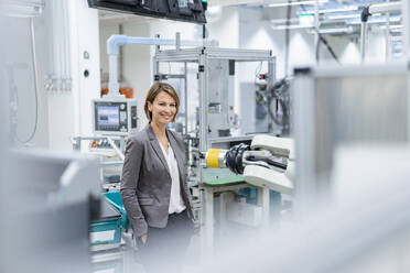 Portrait of a smiling businesswoman in a modern factory - DIGF07840