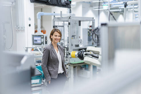 Porträt einer lächelnden Geschäftsfrau in einer modernen Fabrik - DIGF07840
