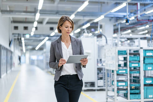 Businesswoman with tablet in a modern factory - DIGF07851