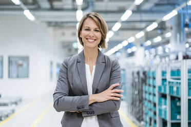 Portrait of a smiling businesswoman in a modern factory - DIGF07869