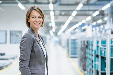Portrait of a smiling businesswoman in a modern factory - DIGF07870