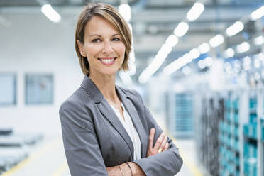 Porträt einer lächelnden Geschäftsfrau in einer modernen Fabrik - DIGF07873
