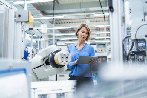 Geschäftsfrau mit Tablet am Montageroboter in einer Fabrik - DIGF07890