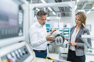 Businesswoman and man talking at assembly robot in a factory - DIGF07893