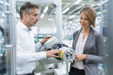 Businesswoman and man talking at assembly robot in a factory - DIGF07895