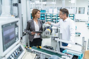 Businesswoman and man talking at assembly robot in a factory - DIGF07899