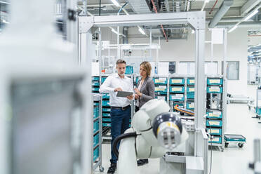 Businesswoman and manwith tablet talking in a modern factory - DIGF07902