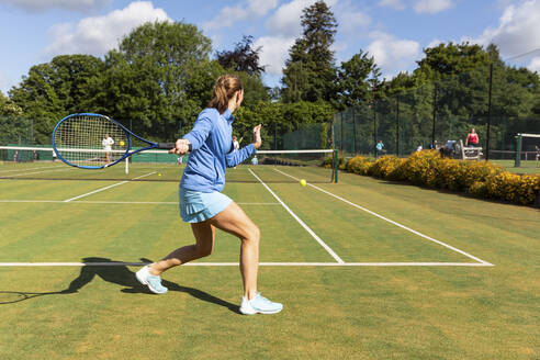 Reife Frau bei einem Tennisspiel auf einem Rasenplatz - WPEF01717