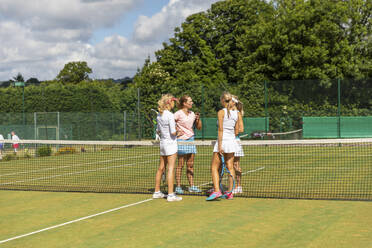 Reife Frauen beenden ein Tennisspiel auf einem Rasenplatz - WPEF01747