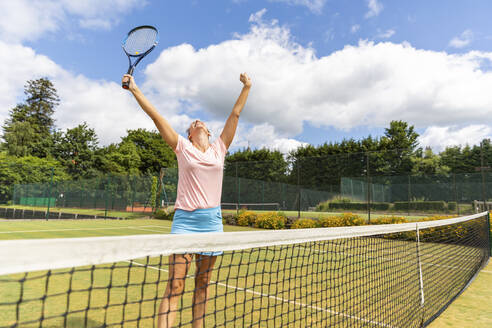 Glückliche Tennisspielerin feiert den Sieg auf dem Rasenplatz - WPEF01774