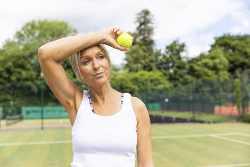 Müde Tennisspielerin macht eine Pause auf dem Rasenplatz im Tennisclub - WPEF01778