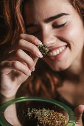 Lächelnde junge Frau mit Marihuana zu Hause - LJF00645