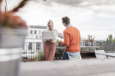 Lässiger Geschäftsmann und Frau mit Laptop treffen sich auf der Dachterrasse - UUF18550