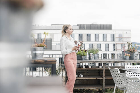 Lässige Geschäftsfrau mit Mobiltelefon auf der Dachterrasse - UUF18552